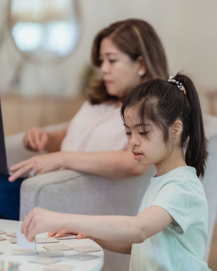 Young girl with Down syndrome playing a board game with her mother