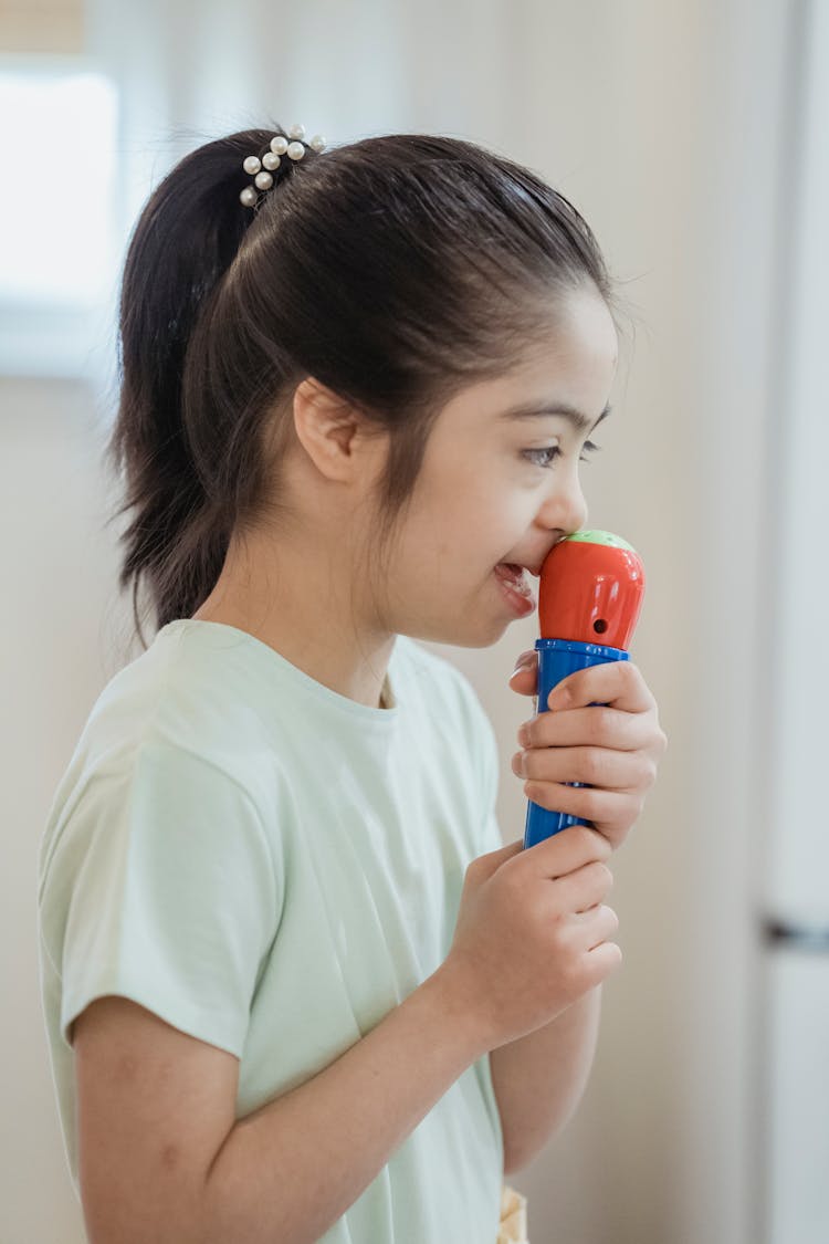 A Young Girl Singing Using A Microphone