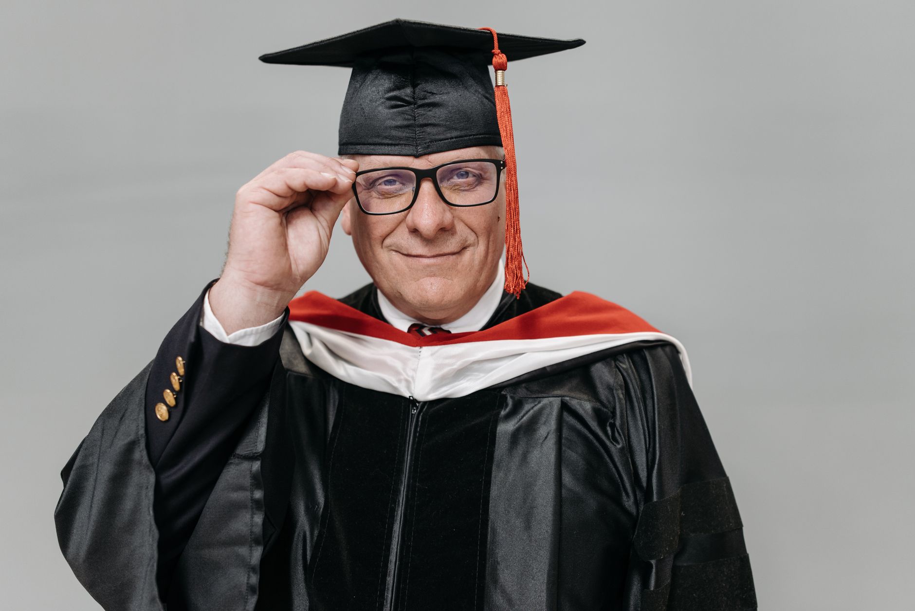 Senior adult celebrating graduation in cap and gown, smiling with pride.
