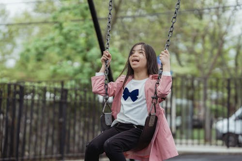 Girl in a White Shirt Sitting on a Swing