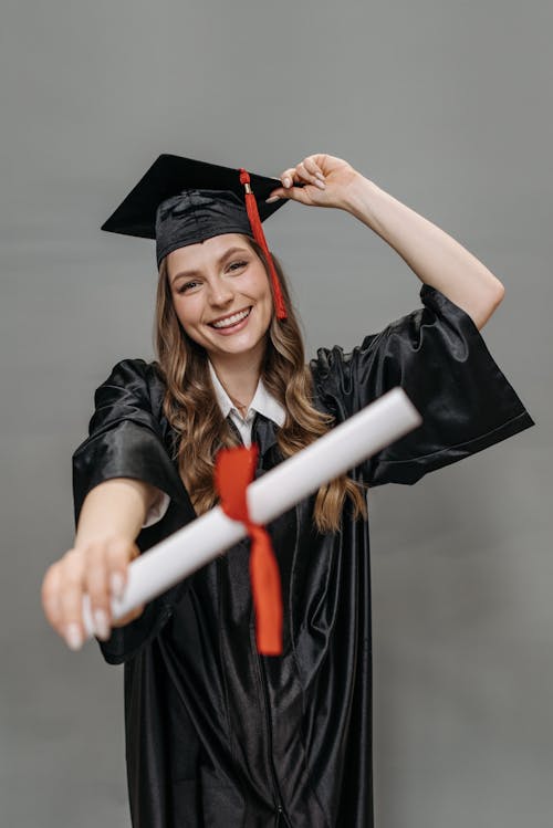 Free  Photo of Woman in Academic Dress Holding Diploma Stock Photo