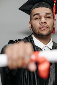 A confident graduate poses with his diploma in a studio setting, symbolizing success.