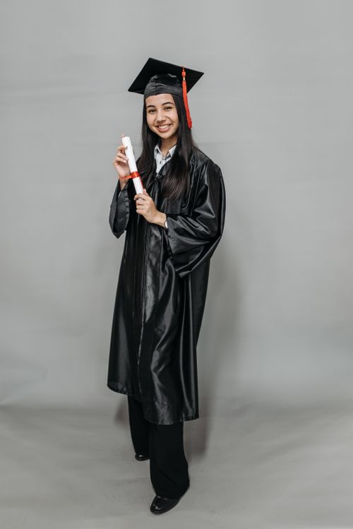 Free Smiling female graduate posing with diploma in graduation attire. Stock Photo