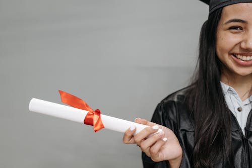 Smiling Woman in Black Graduation Gown Holding a Diploma