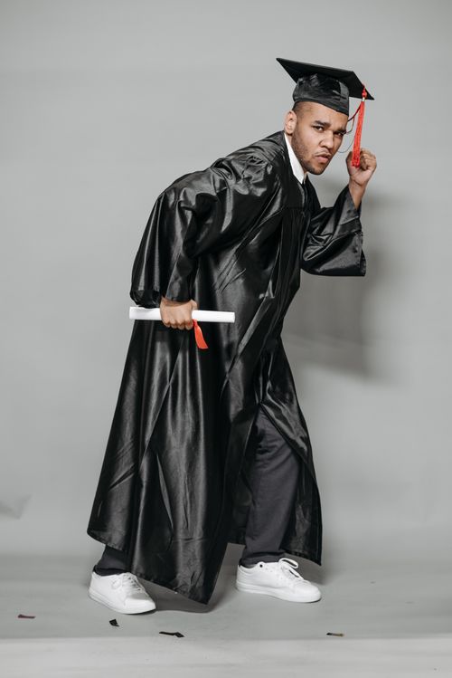 Free A playful graduate posing with a diploma in a studio setting. Stock Photo