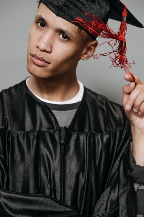 Free Portrait of a young graduate posing with graduation cap and gown, symbolizing success. Stock Photo