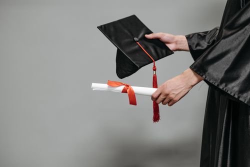 Close-up of hands holding a graduation cap and diploma
