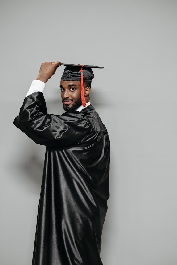 Studio Shot Of Man Holding His Graduation Cap