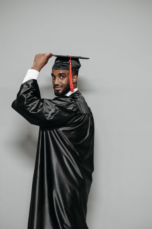 Free Confident graduate smiling and adjusting cap in studio shot. Symbol of achievement and success. Stock Photo