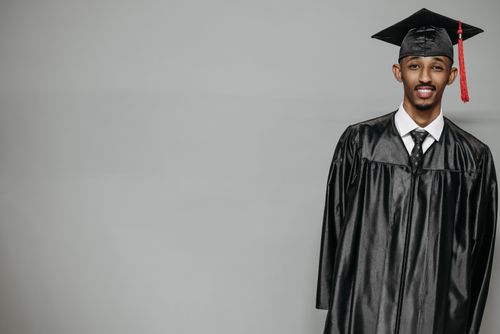 Free Proud graduate in cap and gown smiling in a studio setting Stock Photo