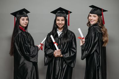 Graduates in caps and gowns holding diplomas