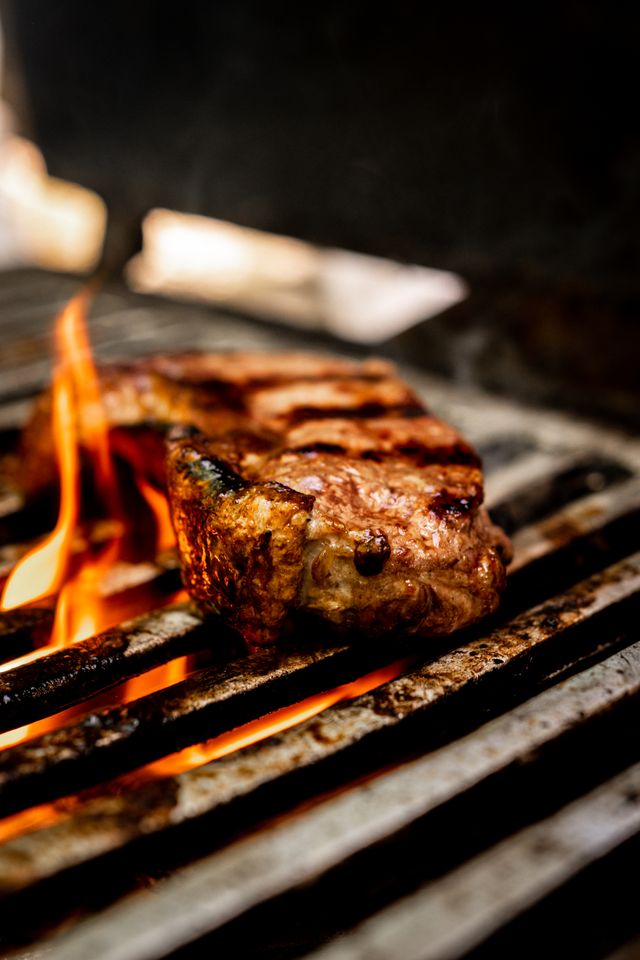 A steak sizzling over open flames on a grill