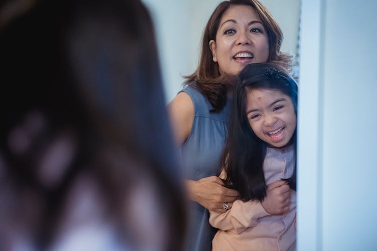 A Mother And Daughter Looking At The Mirror Together