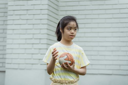 Free A Girl in a Striped Shirt Holding a Ball Stock Photo