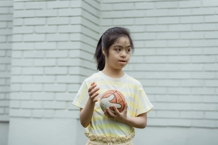 A Girl In A Striped Shirt Holding A Ball