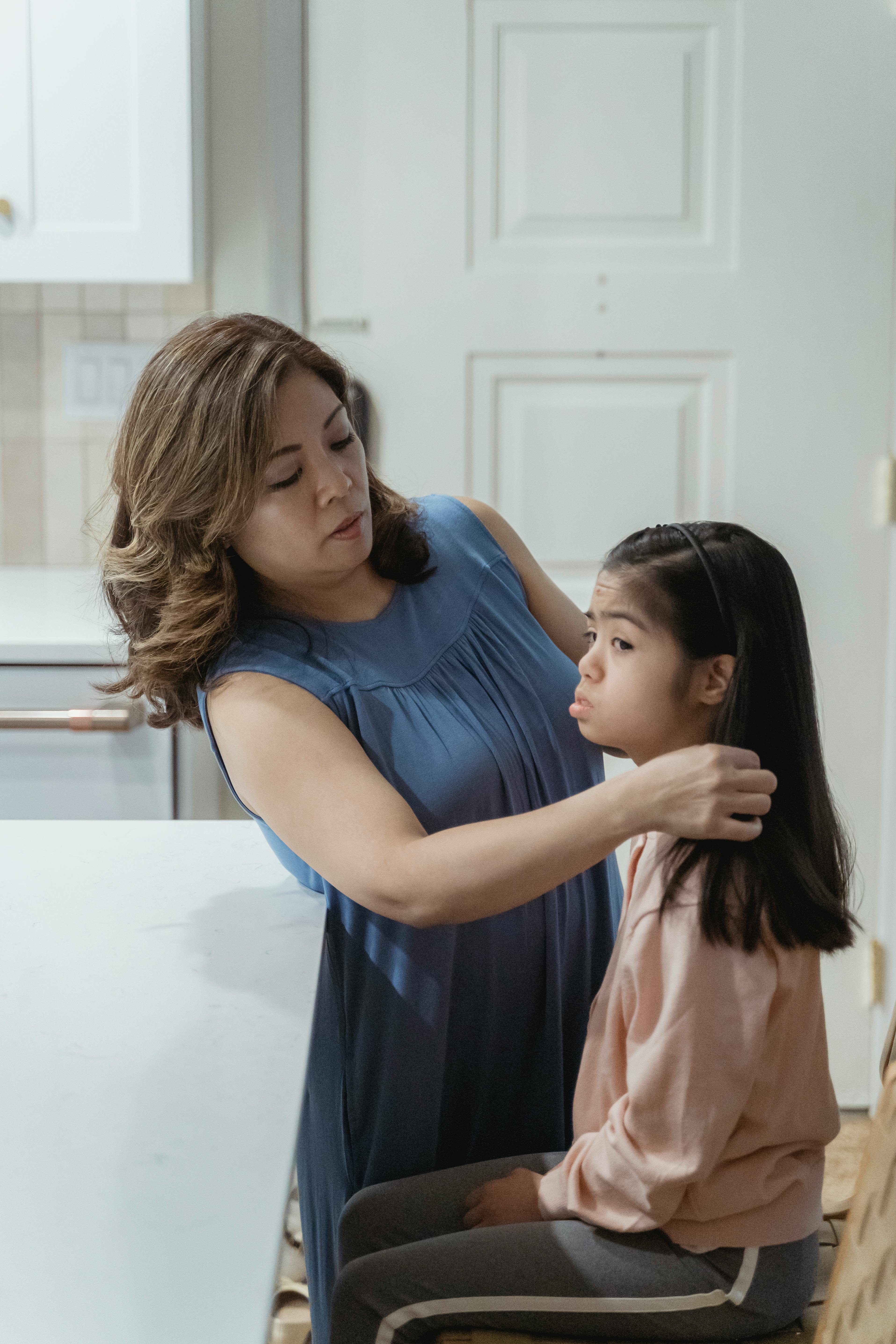 a mother fixing her daughter s hair