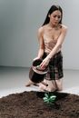 A Woman Kneeling while Watering the Plant