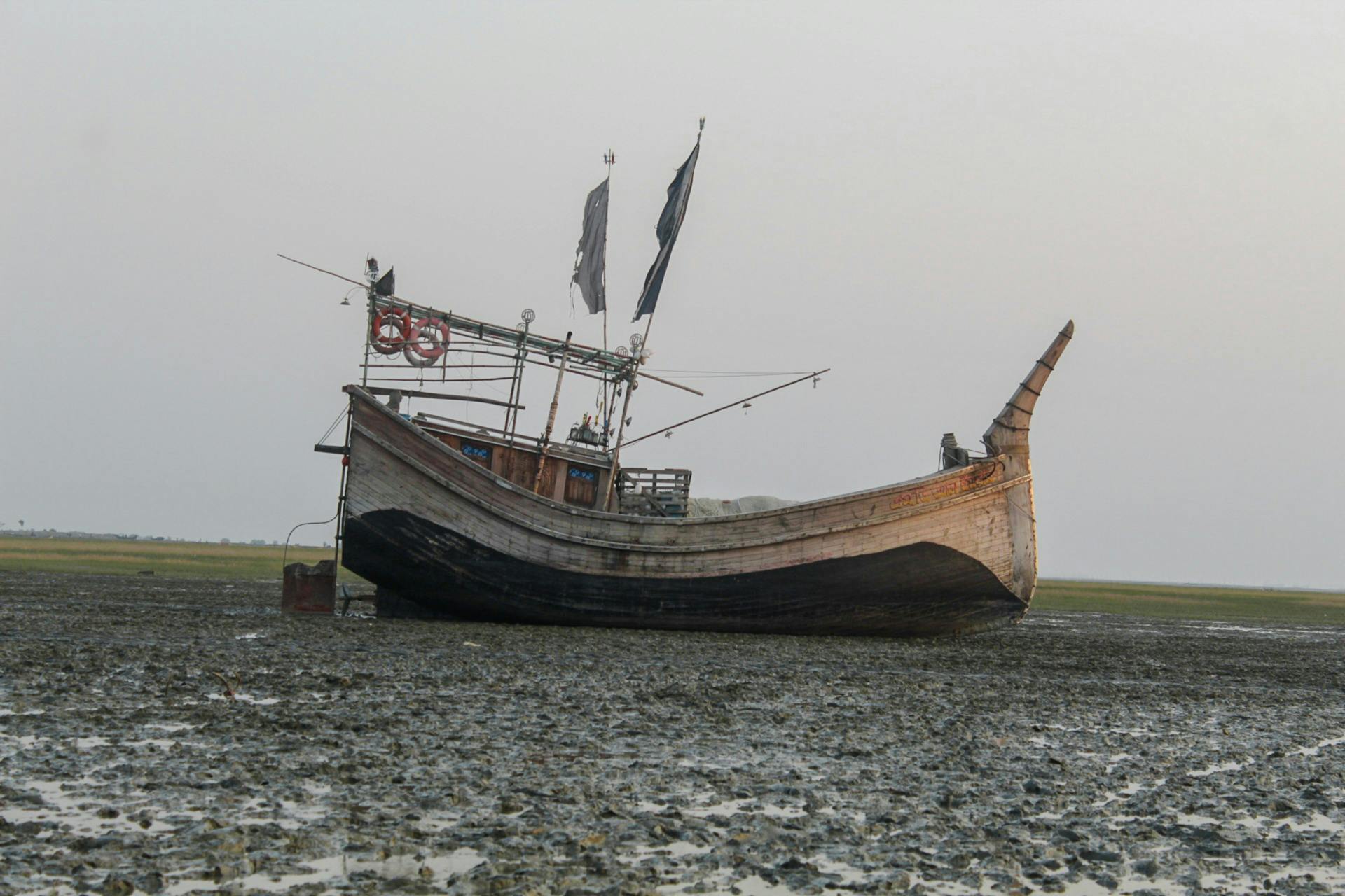 An old, abandoned wooden ship rests on a muddy seashore, creating a vintage maritime scene.