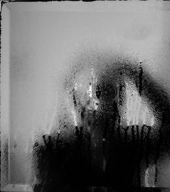 Artistic black and white photo with condensation on glass, evoking a mysterious mood.