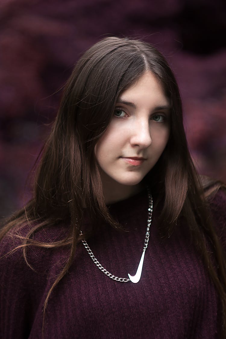 A Woman In Purple Shirt Wearing Silver Necklace