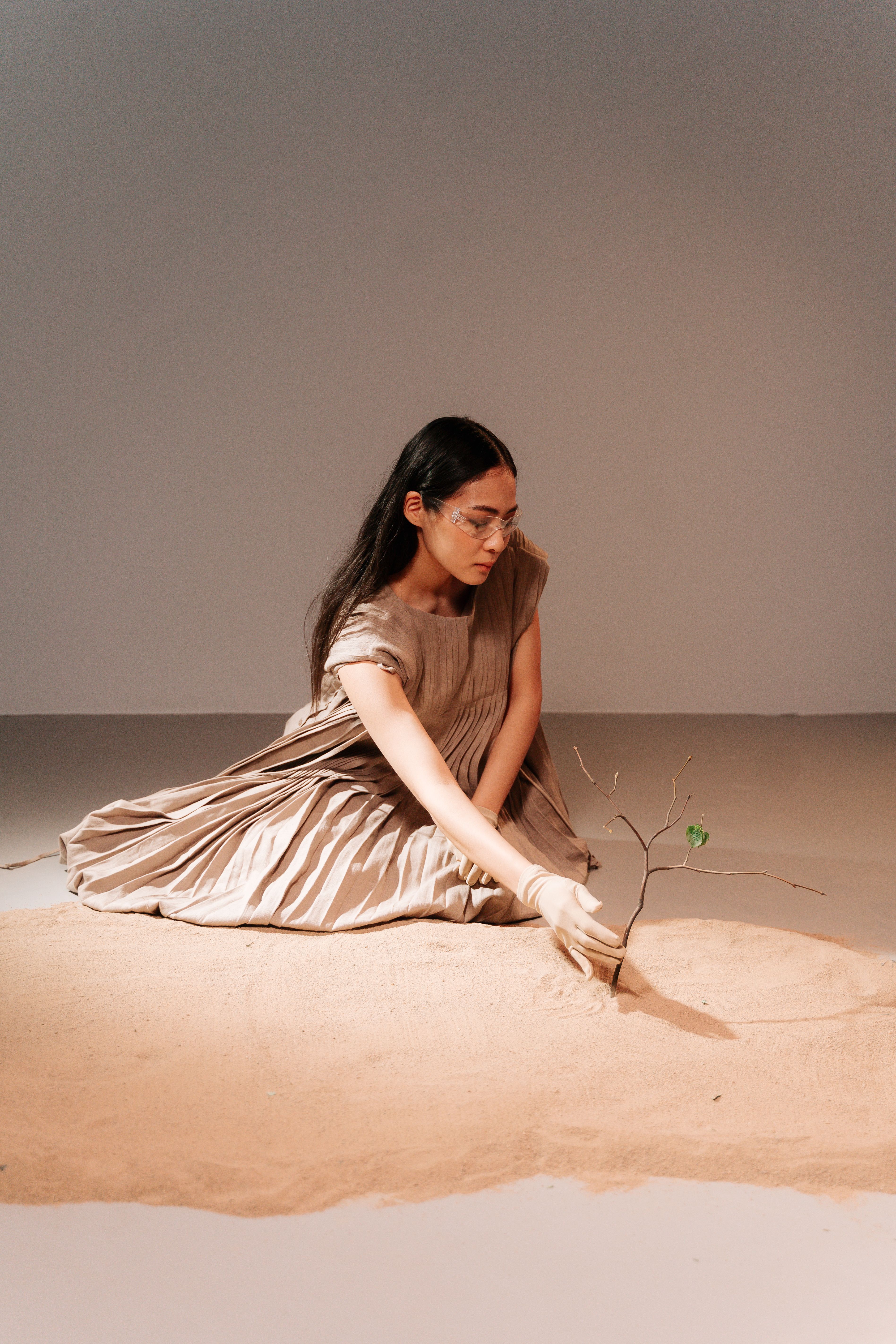 Woman in Beige Dress Sitting on White Sand Touching a Plant · Free ...