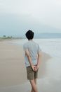 Man in Gray Shirt and Brown Shorts Standing on Seashore