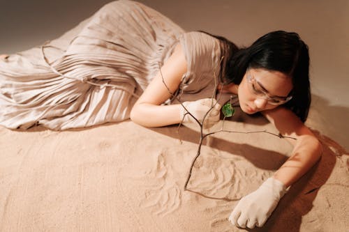 Woman in Brown Dress Lying on Sand