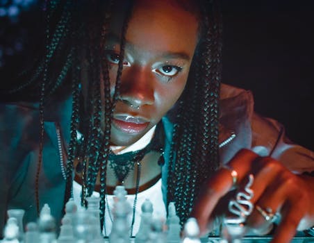 A focused African American woman with braided hair contemplating her next chess move.