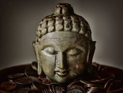 Free Gautama Buddha Bust Surrounded by Coins Stock Photo