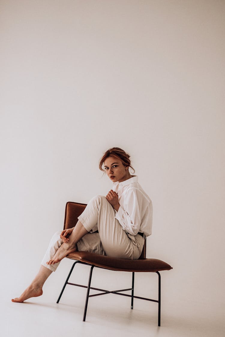 Stylish Woman Sitting On Chair In Studio