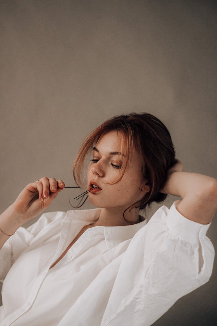 Young Woman With Hairpin In Mouth While Doing Hair