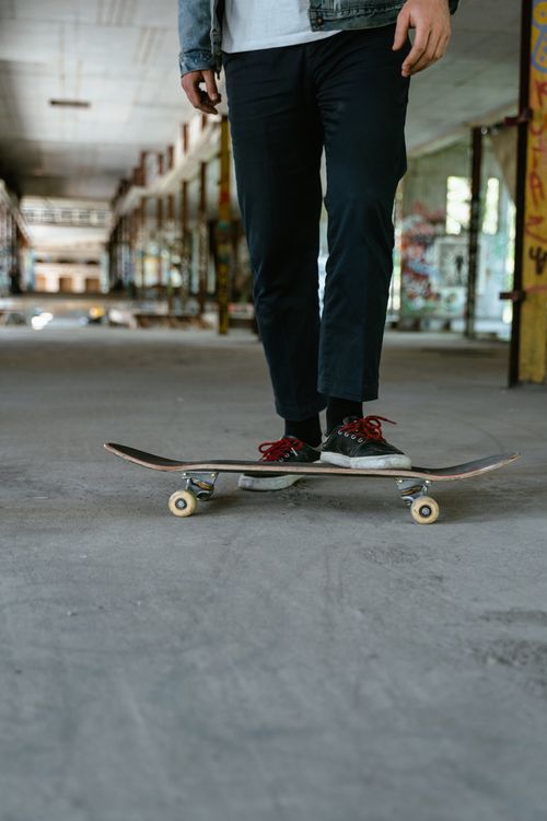 Free A skateboarder stands on a skateboard in an abandoned building with graffiti-covered walls. Stock Photo