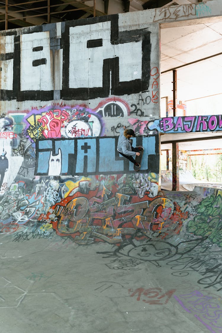 Man Doing Skateboarding Trick On A Wall With Graffiti