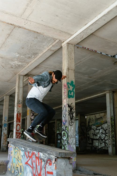 Free Man in Denim Jacket Doing A Jump On A Skateboard Stock Photo