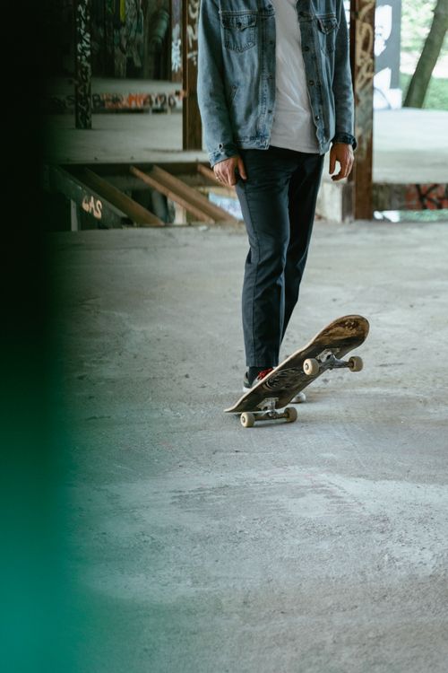 Free A skater standing indoors, holding their skateboard in a casual pose. Stock Photo