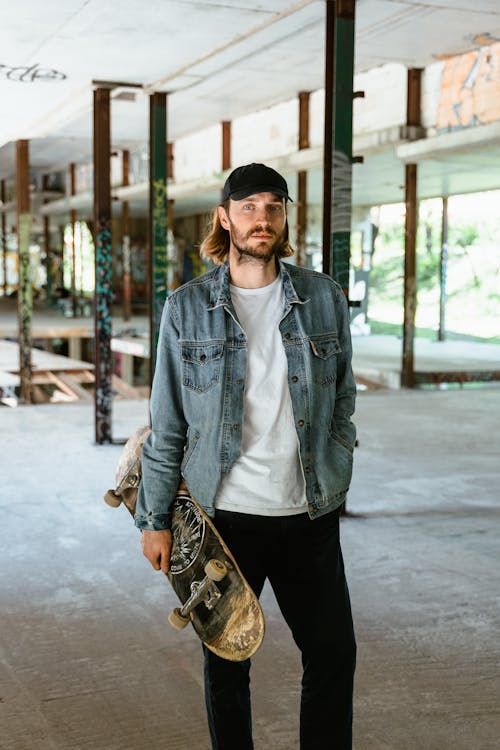 Man in White Crew Neck T-Shirt With Denim Jacket Holding A Skateboard