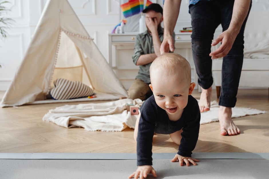 Bebê brincando no chão cercado de brinquedos em ambiente aconchegante