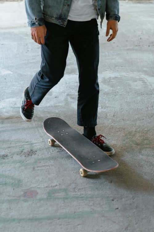Free Close-up of a skateboarder's feet in jeans, showcasing skateboarding motion and style. Stock Photo