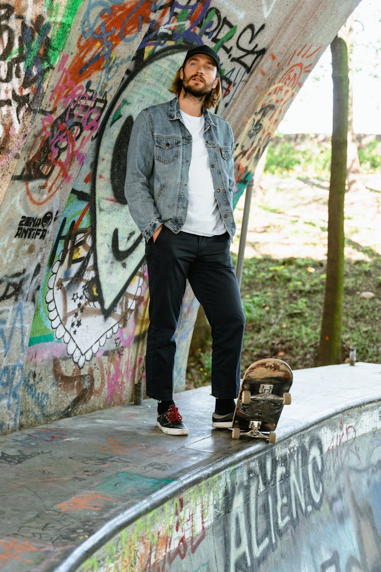 A Man In Denim Jacket Stepping On The Skateboard While Standing