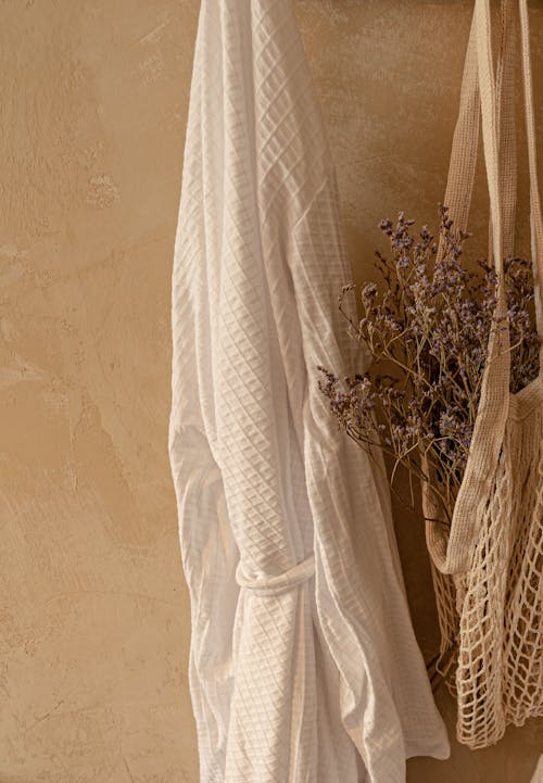 A Hanged White Robe beside a Net Bag with Dried Flowers