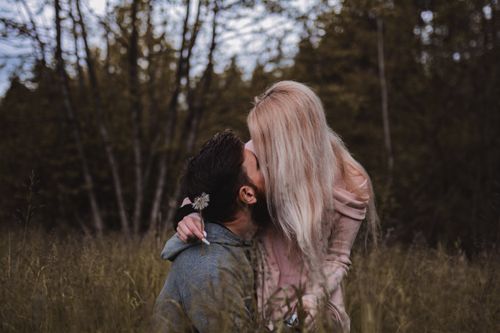 Free A couple shares an intimate moment with a kiss amidst a serene forest backdrop. Stock Photo