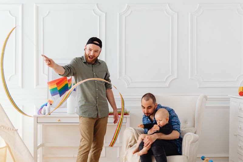 A joyful family scene with LGBTQ pride flags, indoors, capturing love and unity.