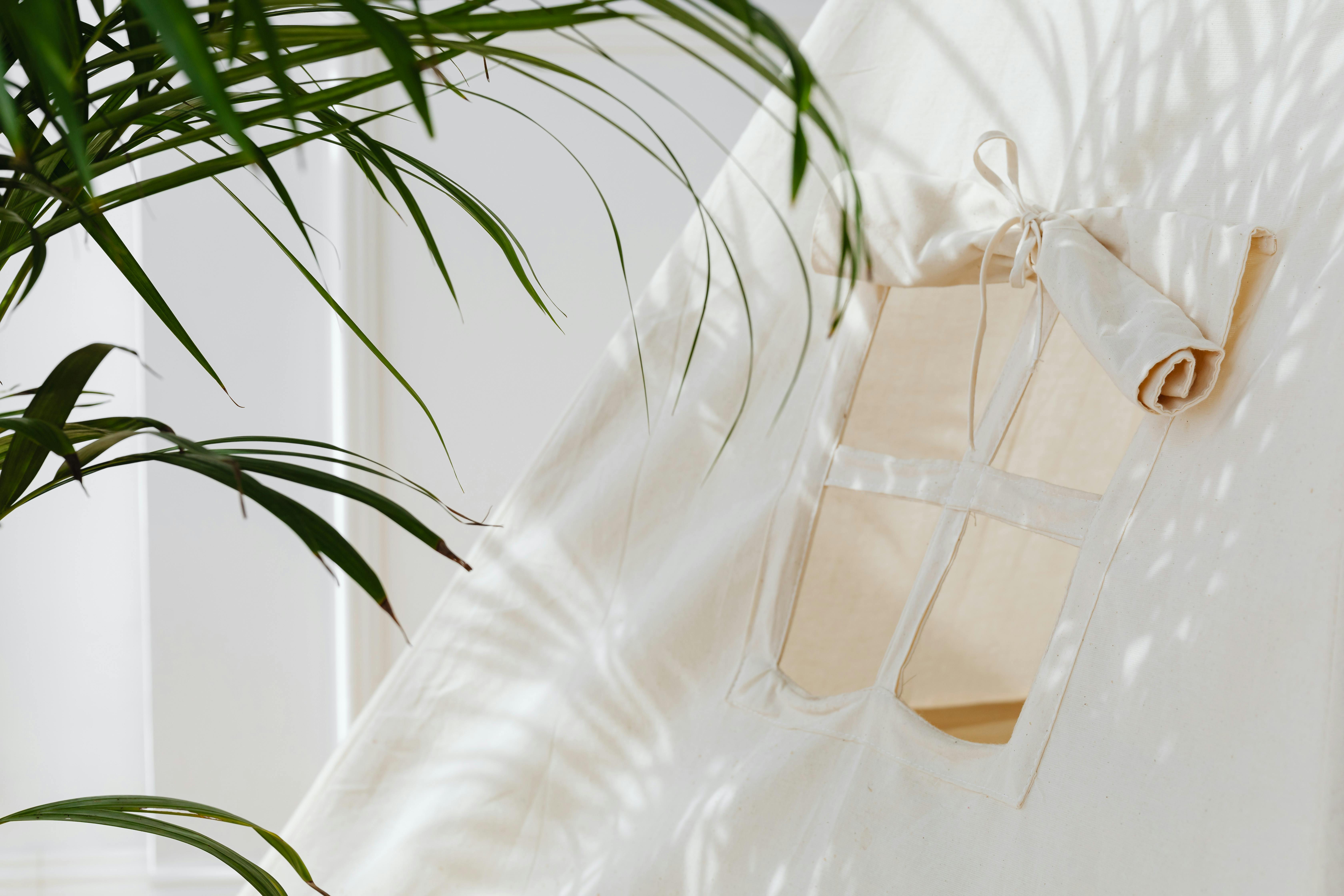 Bright and airy interior shot showcasing a canvas tent and palm leaf shadow, perfect for home decor inspiration.