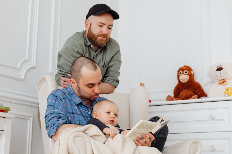 Men Reading A Book With Their Baby