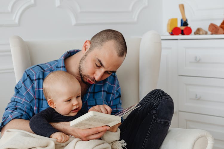 A Man Reading Book With His Baby