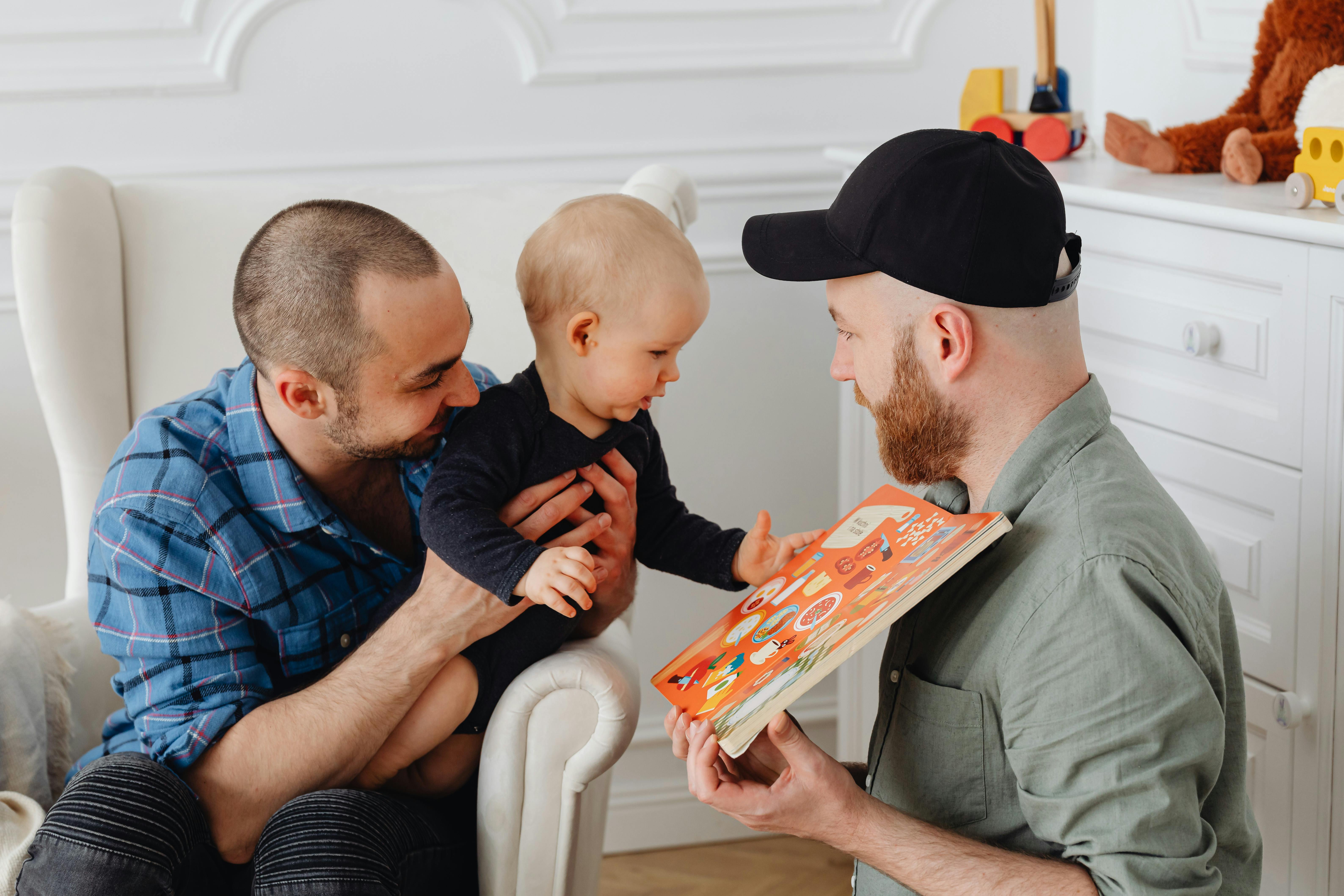 a same sex couple taking care of their child while showing a book