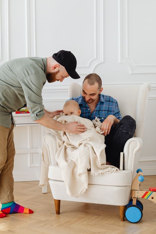 Free Two fathers spending quality time with their baby in a warm indoor setting. Embracing parenthood. Stock Photo