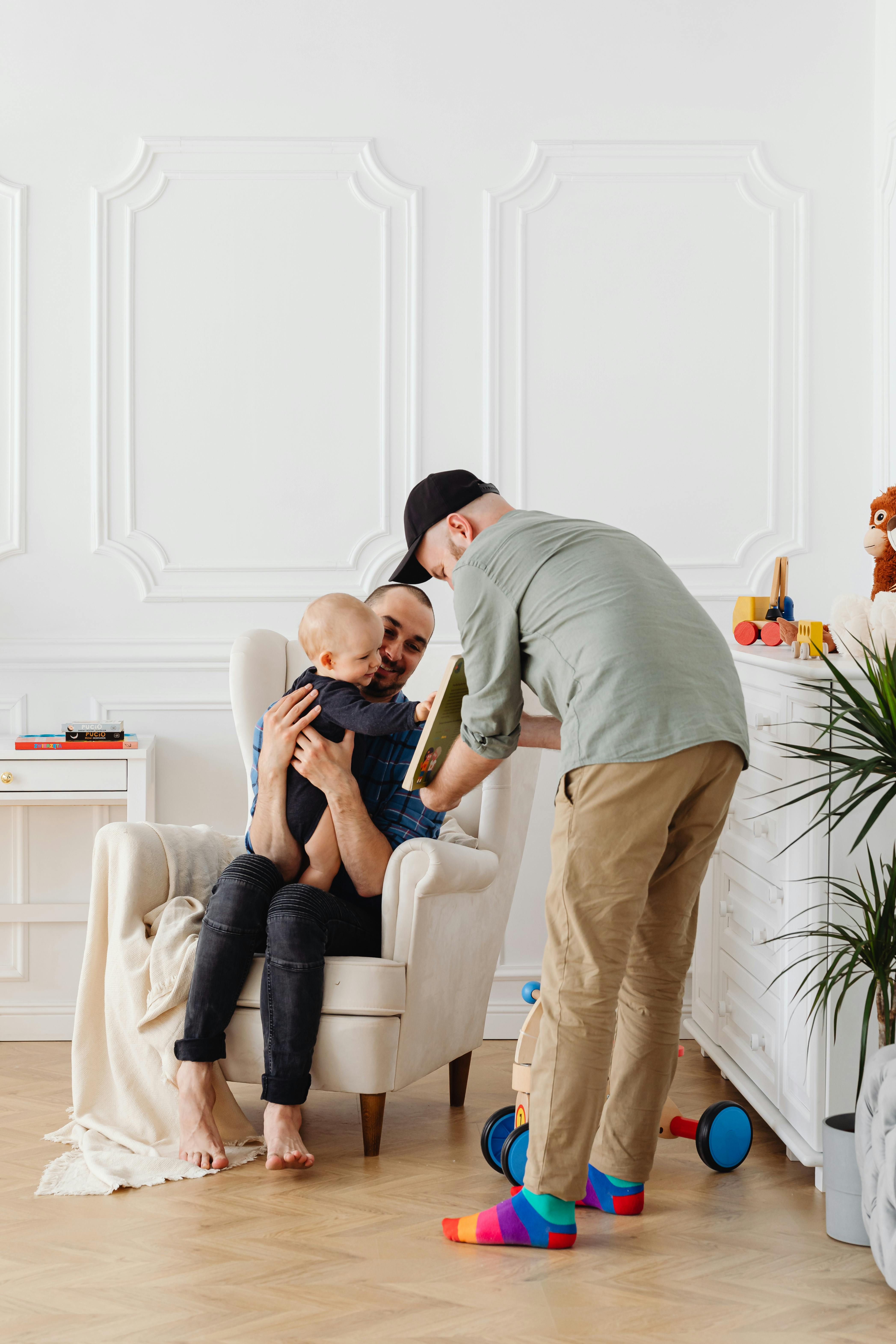 A tender family moment with two fathers enjoying time with their child indoors.