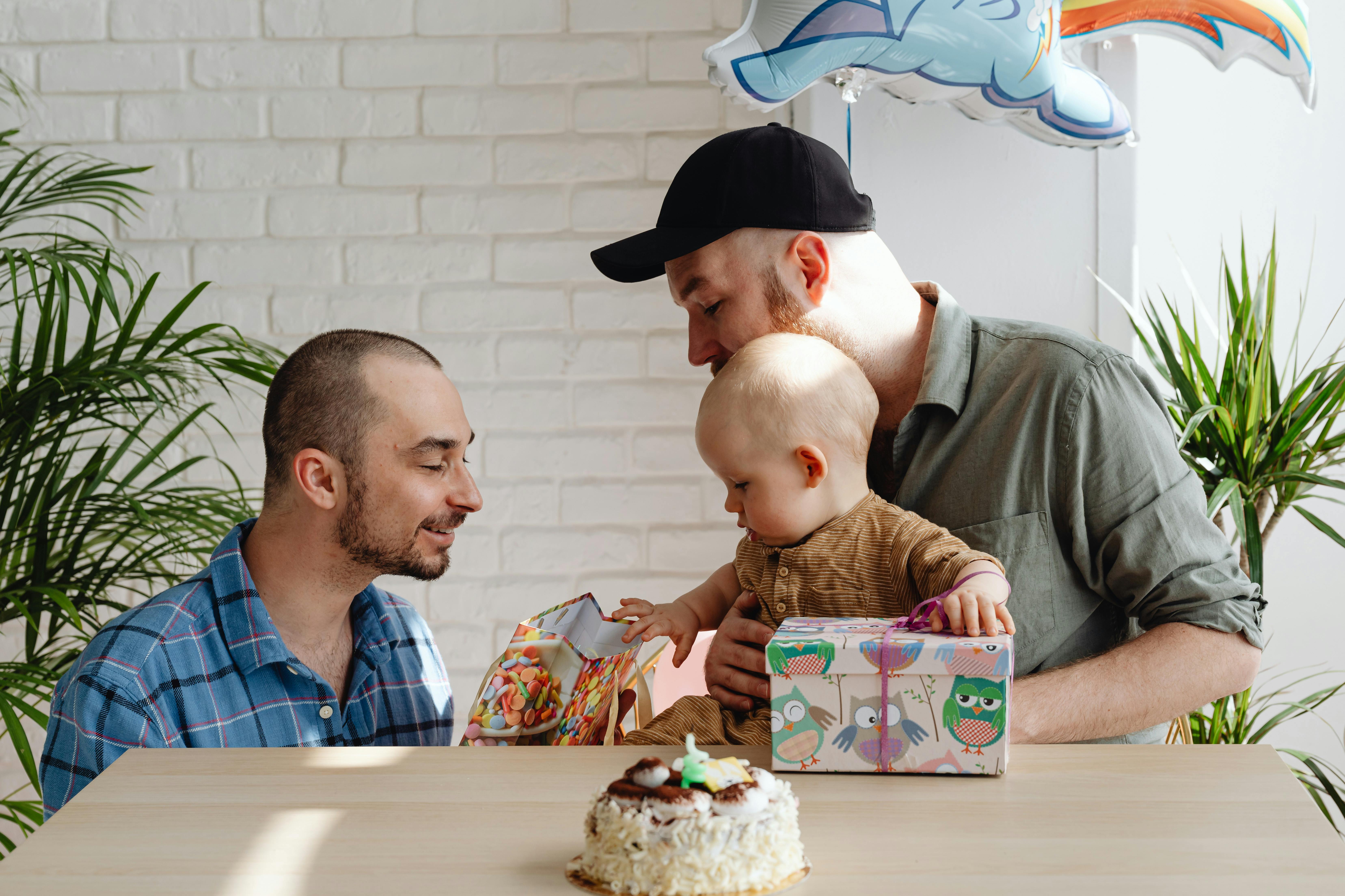 a same sex couple looking at the paper bag with their son