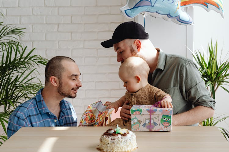 A Same Sex Couple Looking At The Paper Bag With Their Son